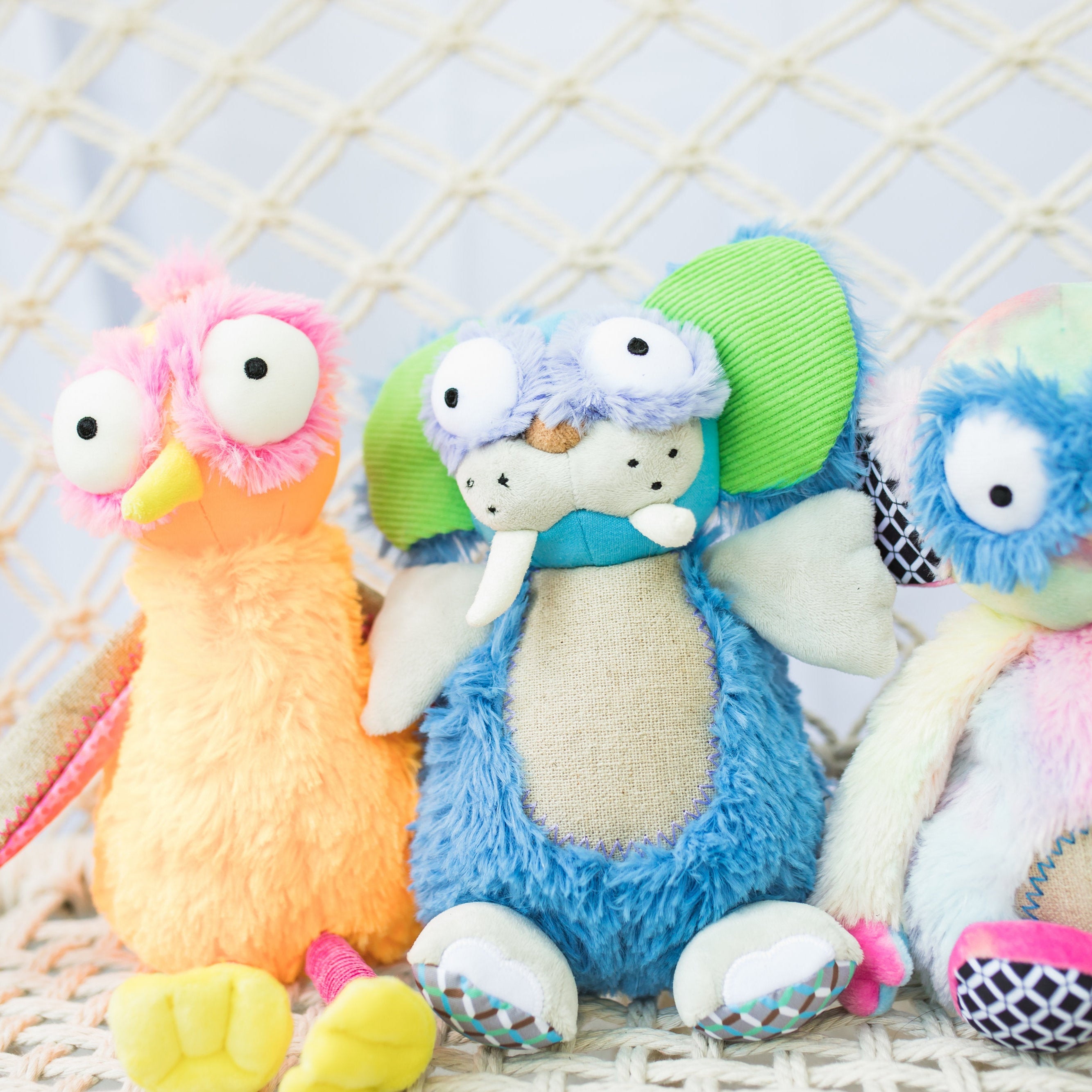 Colorful plush toys with large eyes on a textured surface